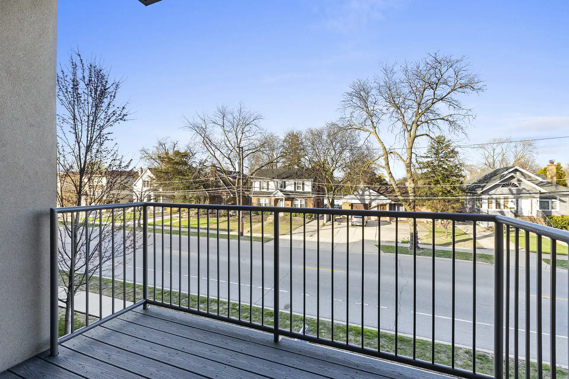 private balcony with hardie plank style floor, stucco walls, and round metal railing.